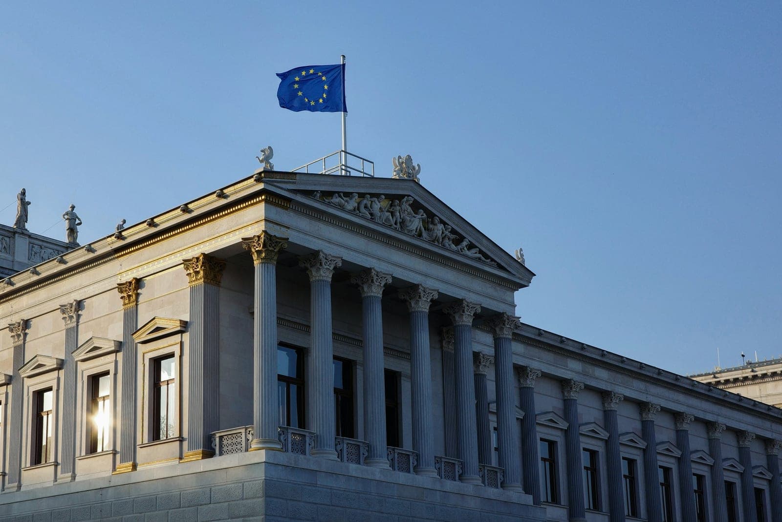 Neoclassical government building with Corinthian columns and a sculpted pediment against a clear blue sky