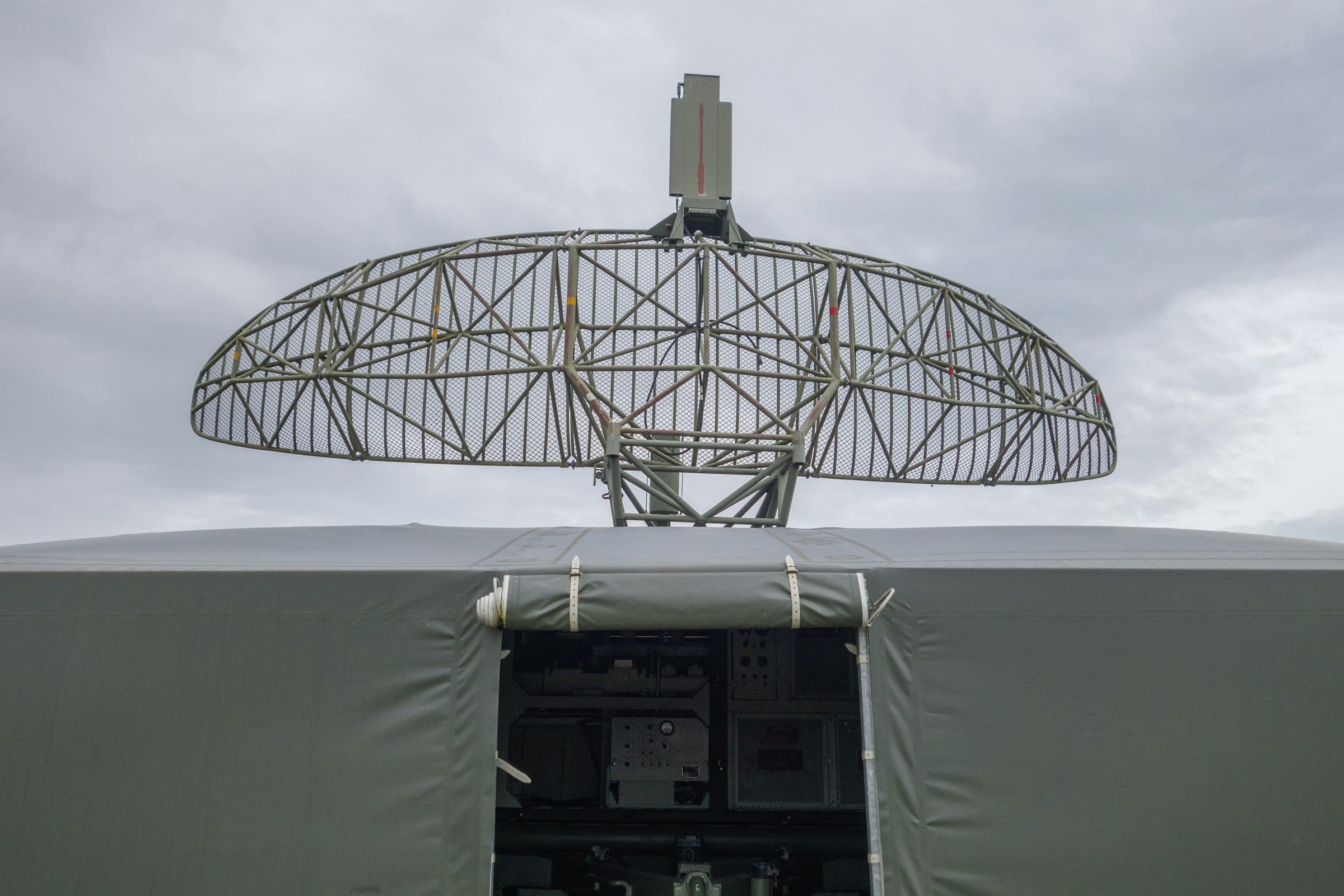 Lattice radar antenna mounted on top of a vehicle shelter against a pale sky