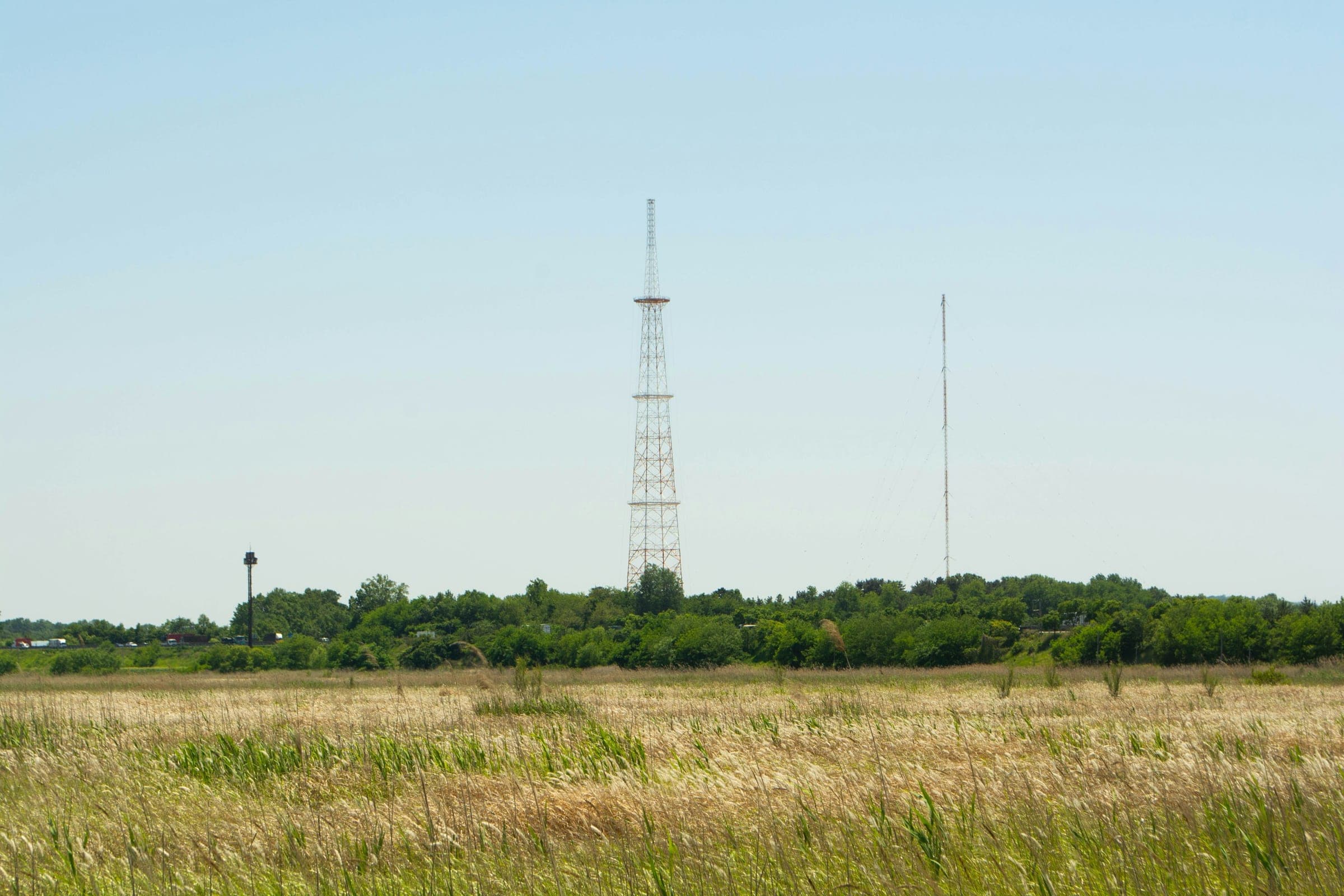 Flat grassland under a clear sky with lattice communication masts on the horizon