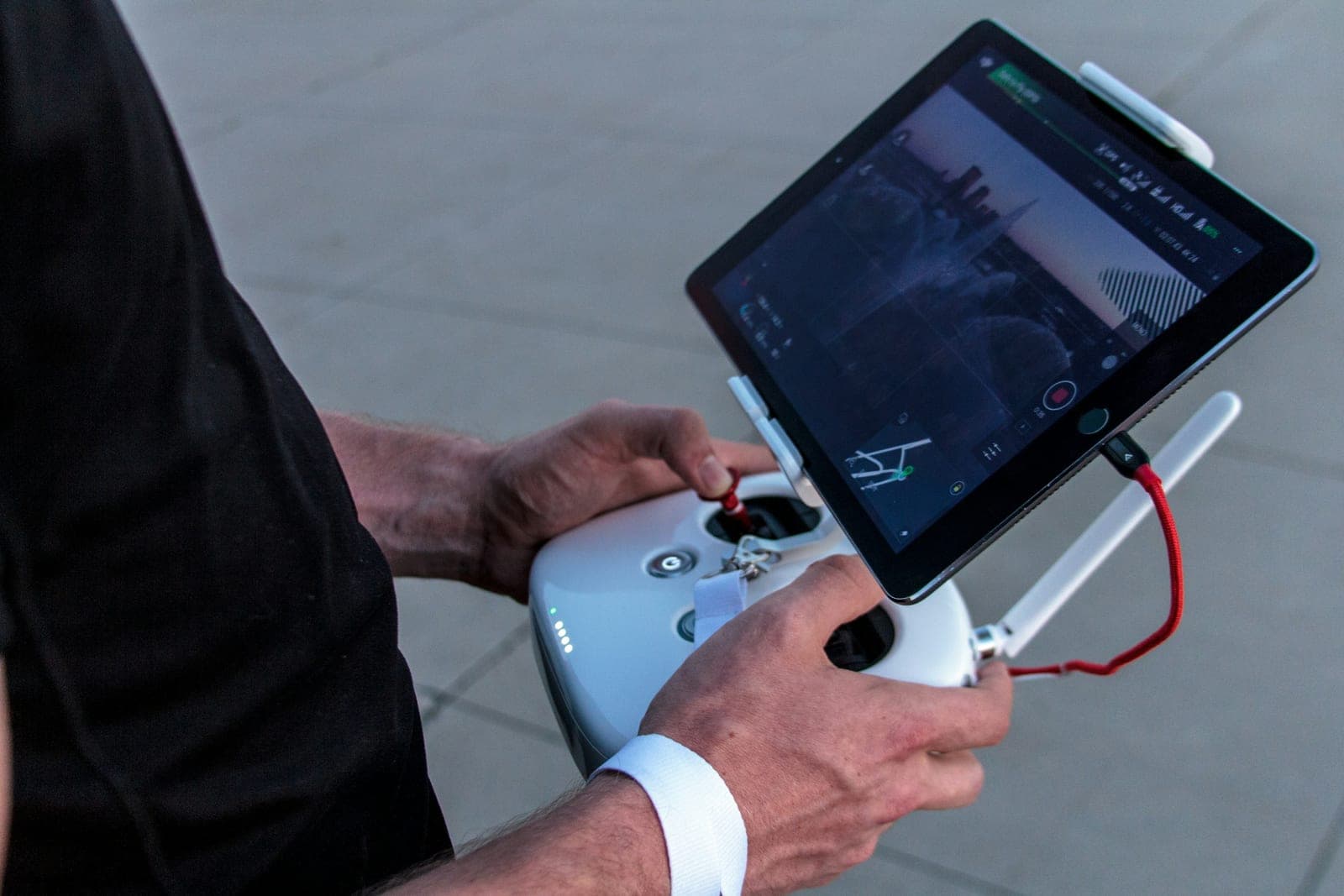 Hands on a drone ground controller with a tablet showing a map view